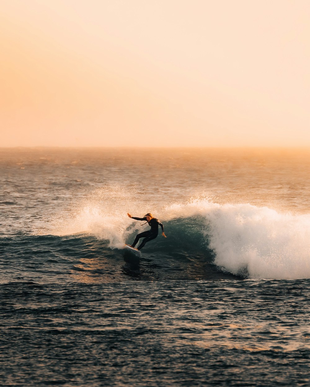 A surfer carving a turn at sunset