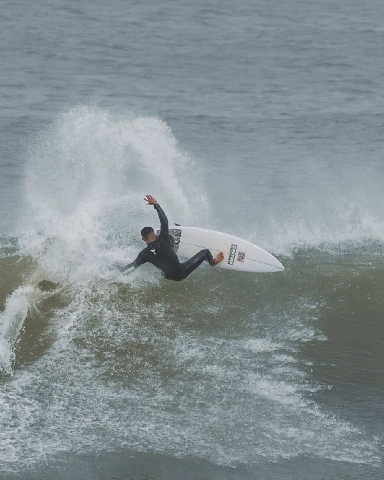 Lucas surfing a turn in a spray of white water