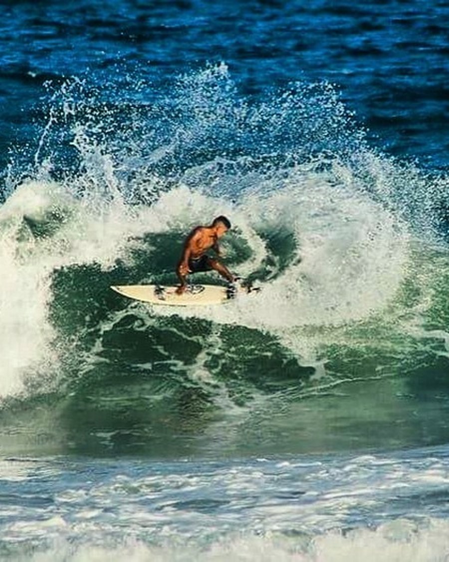 A surfer carving a turn in teal water